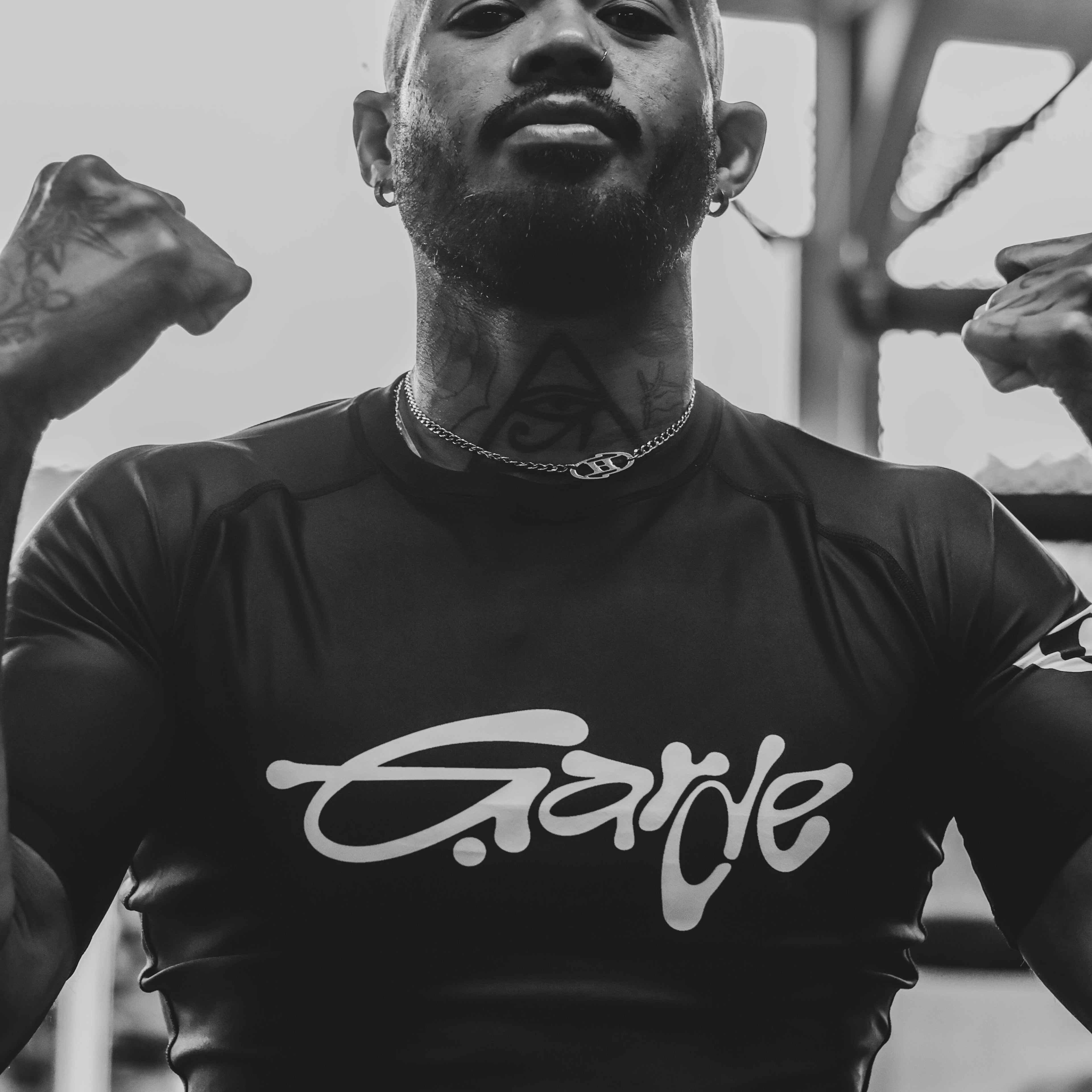 BJJ athlete wearing Garde Collective OG rashguard at the gym, flexing muscles.